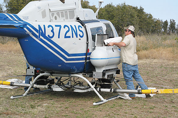 Filling hopper on helicopter with fire ant bait